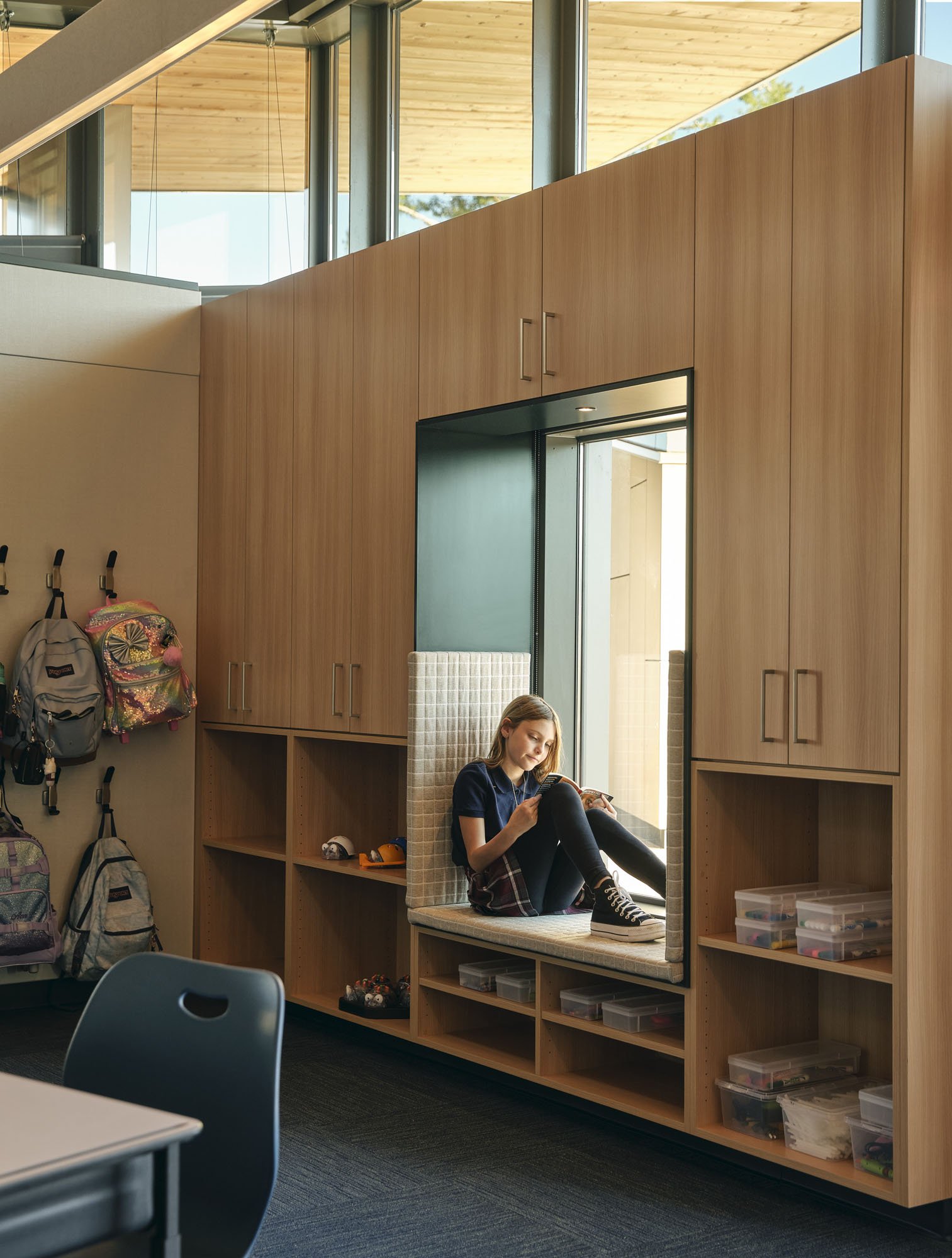 a kid sitting in a window nook inside at school