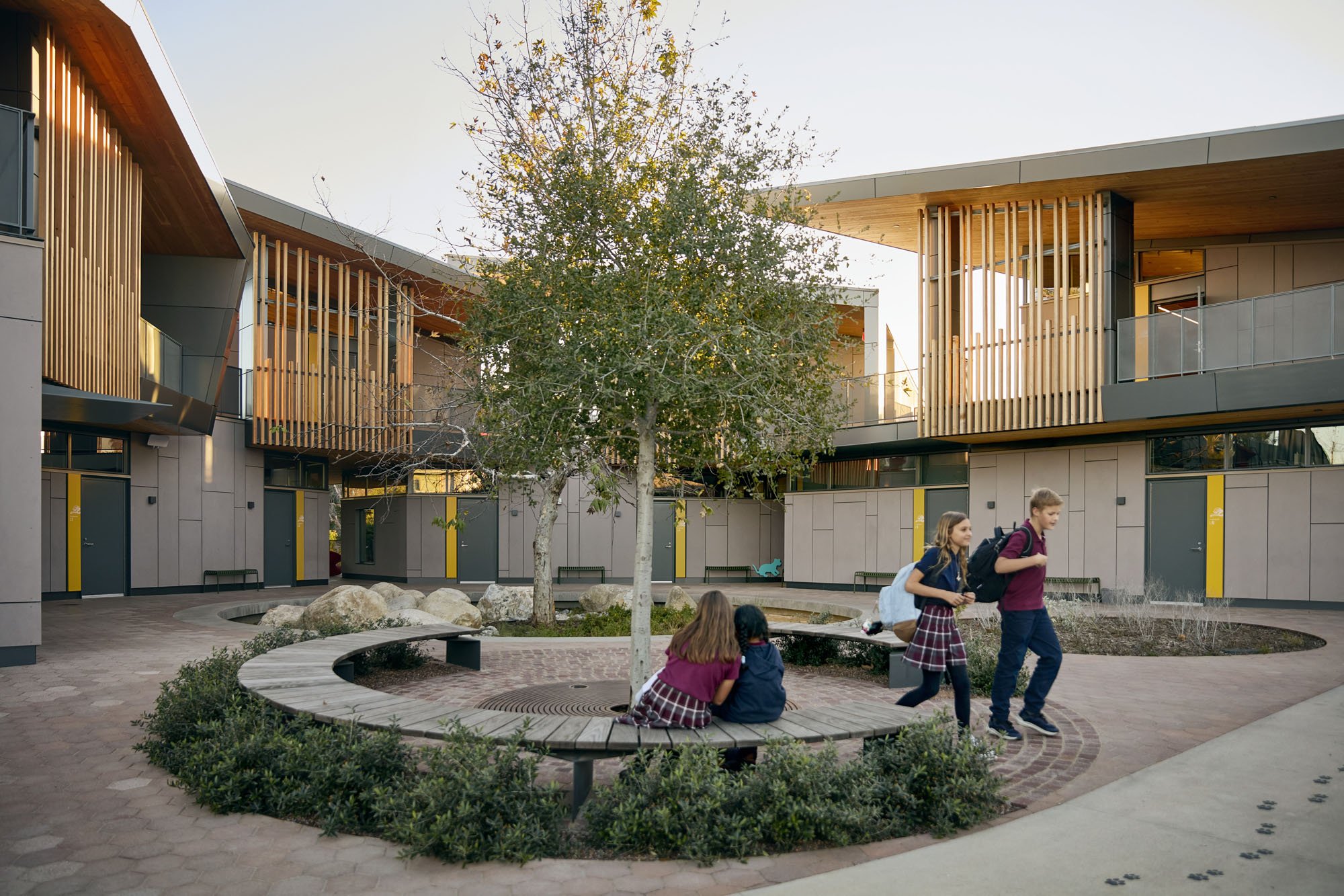 Kids sitting on a bench in an outdoor courtyard at a school