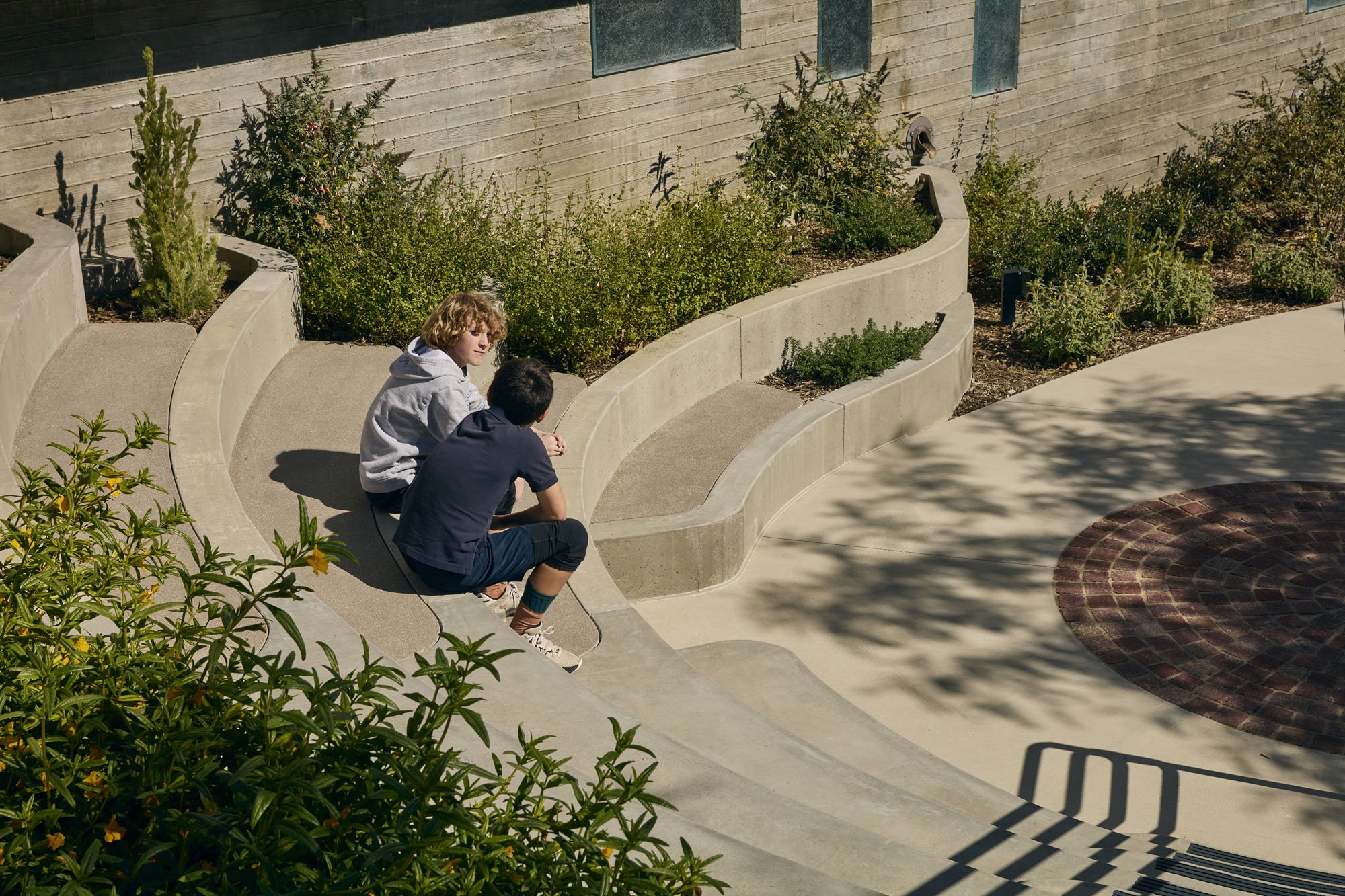 kids sitting in outdoor landscaping at their school