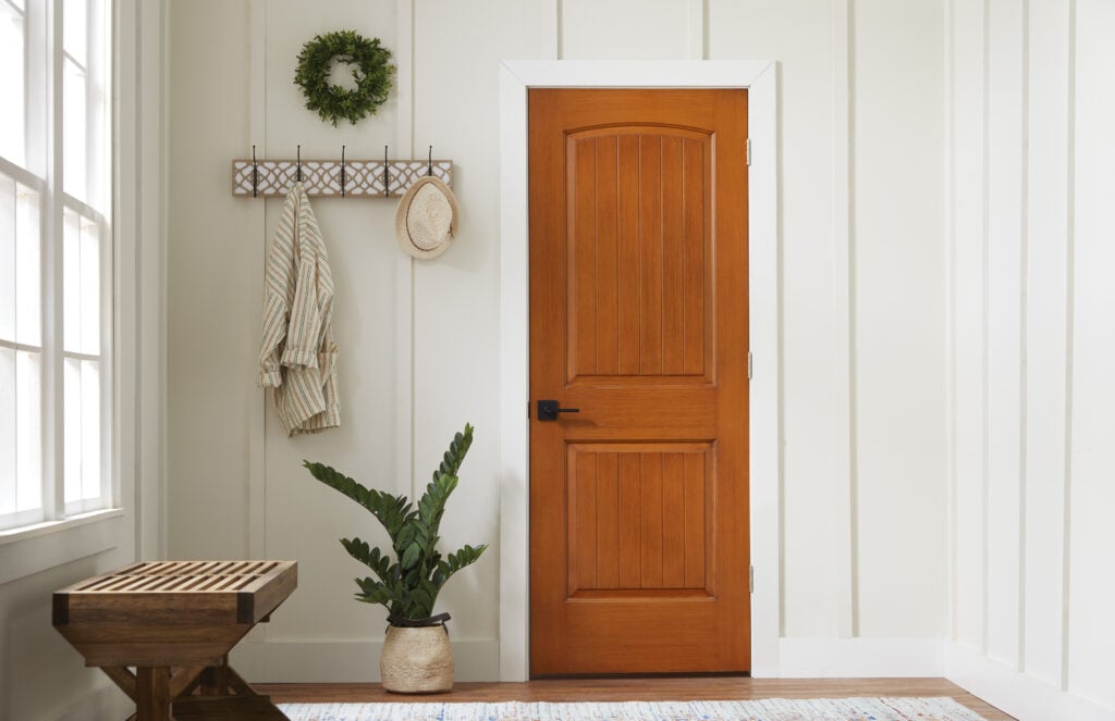 image of the interior of an entry way with white walls and a wood door