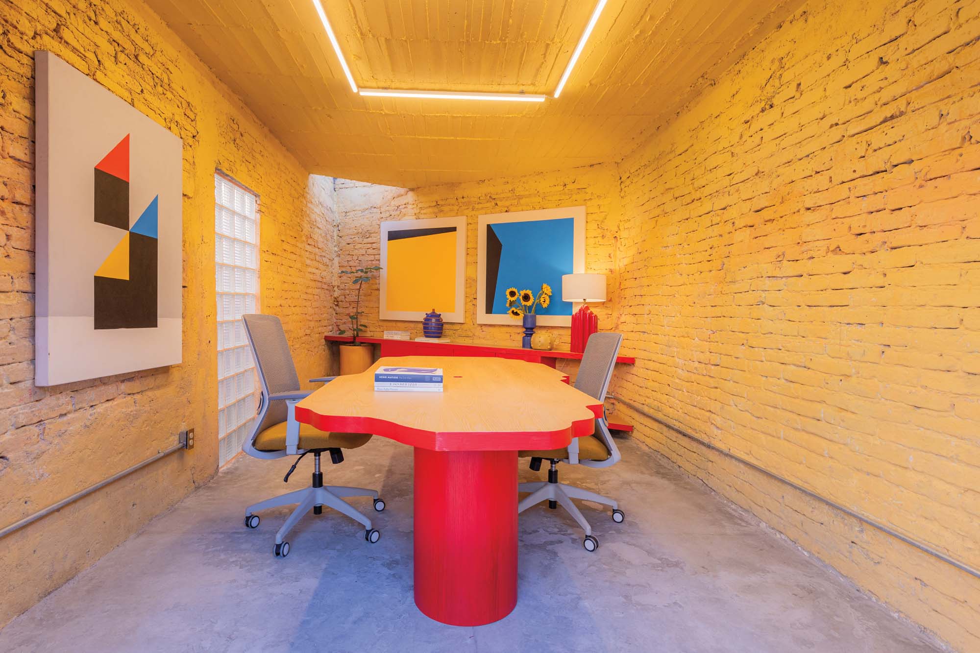 yellow brick interior room with a unique shaped desk in the middle