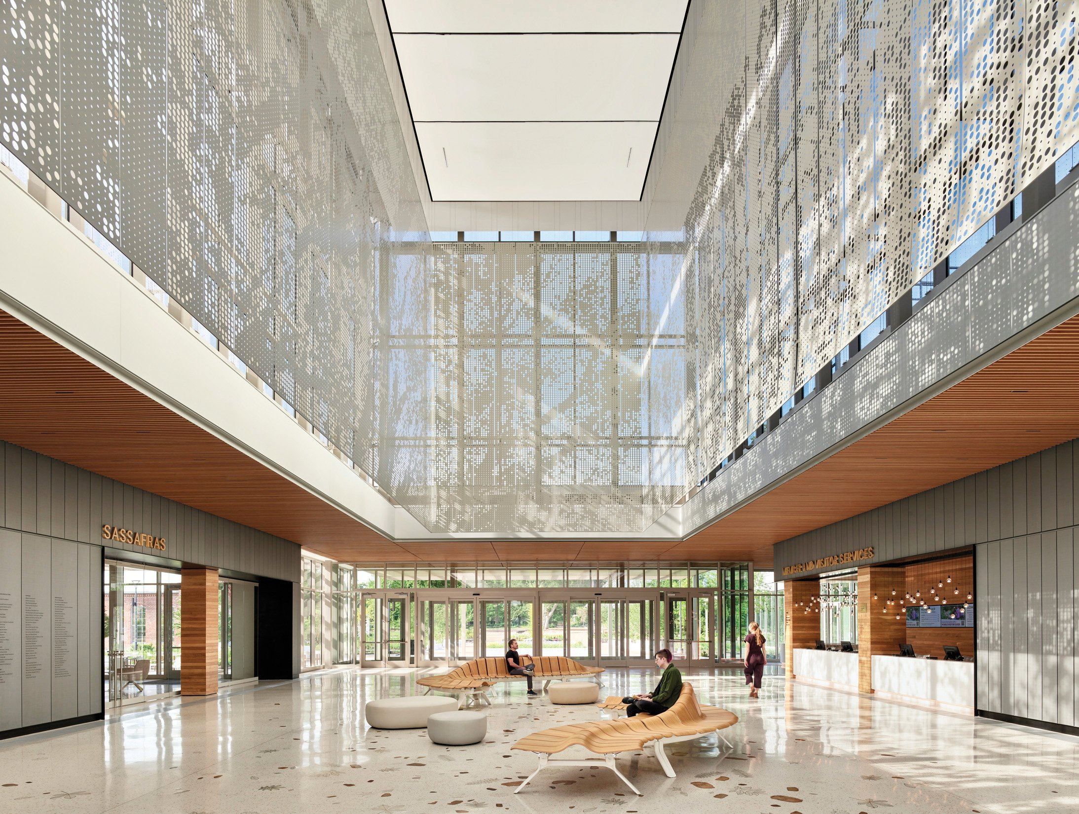 photo of the interior. of a botanic garden lobby. with people sitting on benches in an open atrium