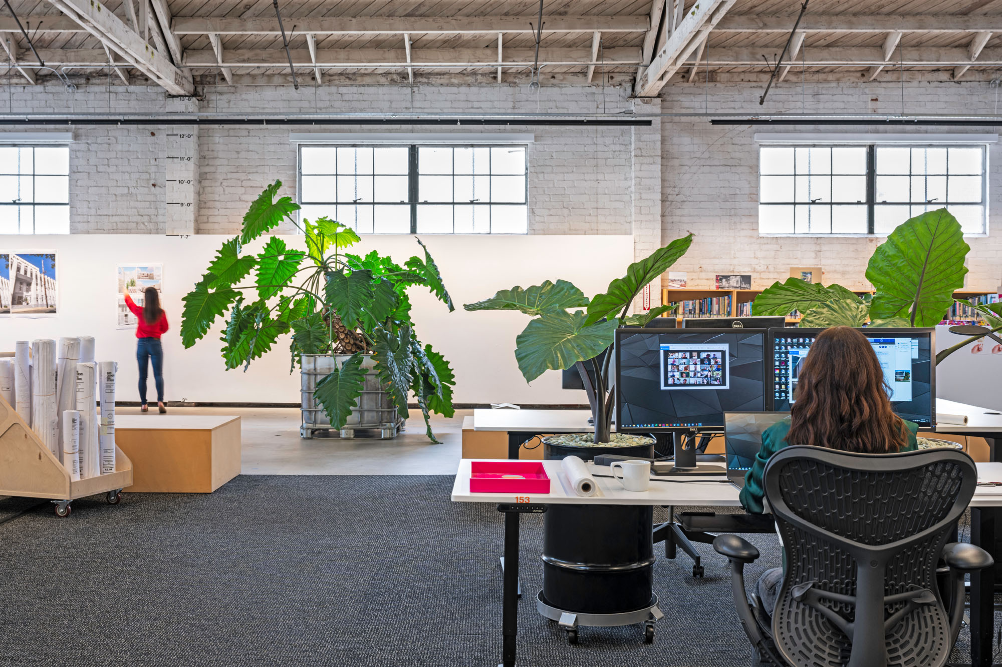 interior open plan workplace with person working at desk and another person working at a board