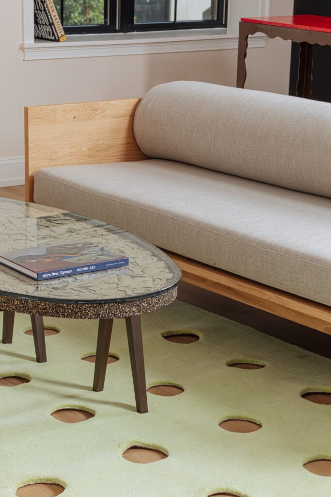 A grey couch on a light green rug with an oval coffee table in front of it